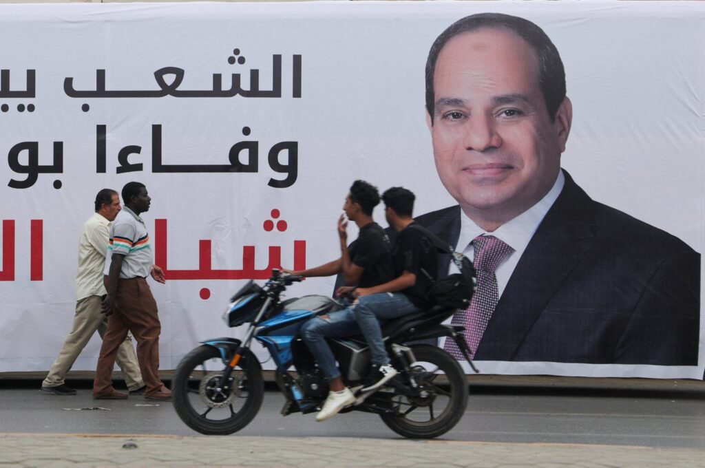 People walk past a banner depicting Egypt's President Abdel Fattah el-Sissi, as people prepare for a rally to support him in the upcoming presidential election in December, in Cairo, Egypt, Oct. 2, 2023. (Reuters Photo)