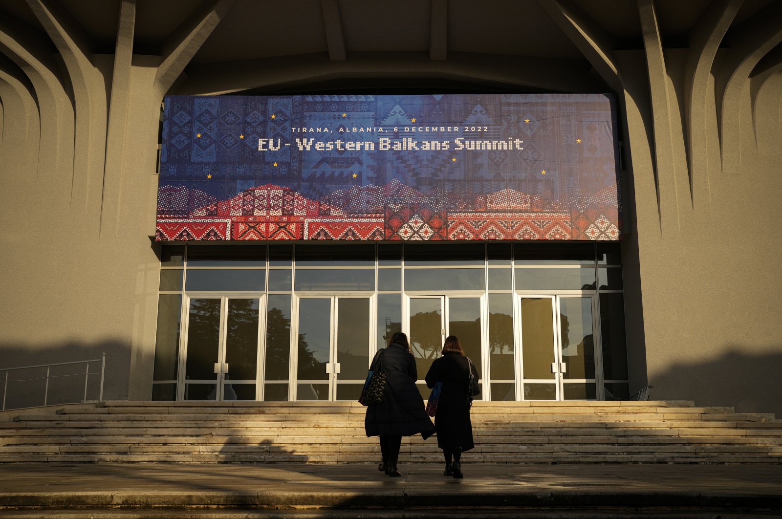 People walk outside the venue of the EU Western Balkans Summit, in Tirana, Albania, Dec. 5, 2022. (AP Photo)