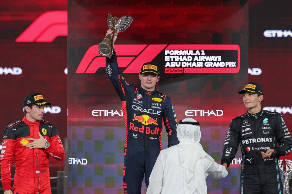 Ferrari's Monegasque driver Charles Leclerc (L) and Mercedes' British driver George Russell (R) watch as Red Bull Racing's Dutch driver Max Verstappen celebrates with the winner's trophy on the podium after the Abu Dhabi Formula One Grand Prix at the Yas Marina Circuit, Abu Dhabi, UAE, Nov. 26, 2023. (AFP Photo)