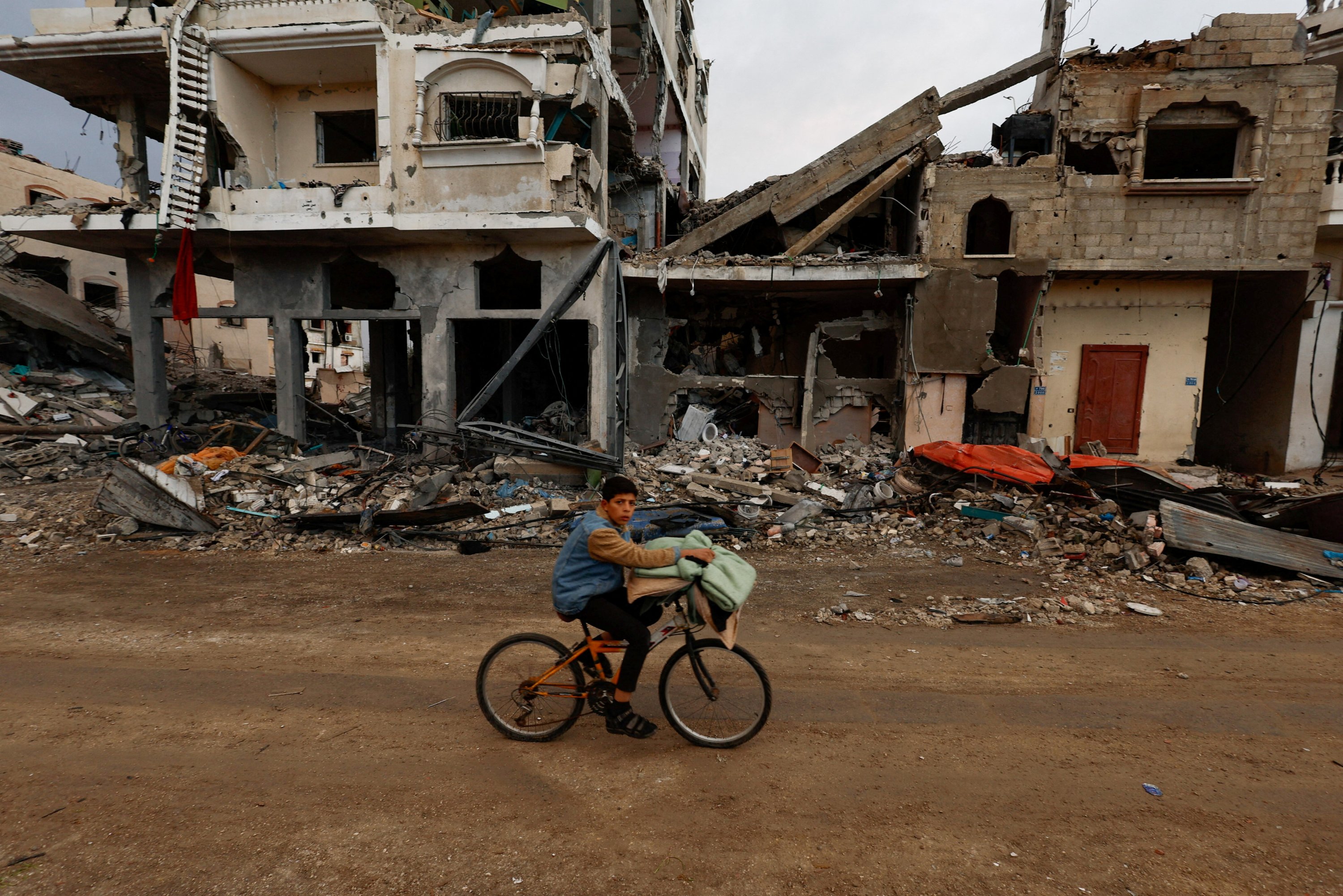 303195 A Palestinian boy rides a bicycle next to the rubble of a house hit in an Israeli strike in Khan Younis, southern Gaza Strip, Nov. 27, 2023. (Reuters Photo)