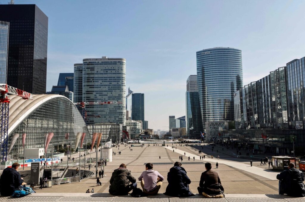 People sit on stairs on the Parvis de la Defense in Paris' business district of La Defense, outside Paris, March 23, 2021. (AFP Photo)