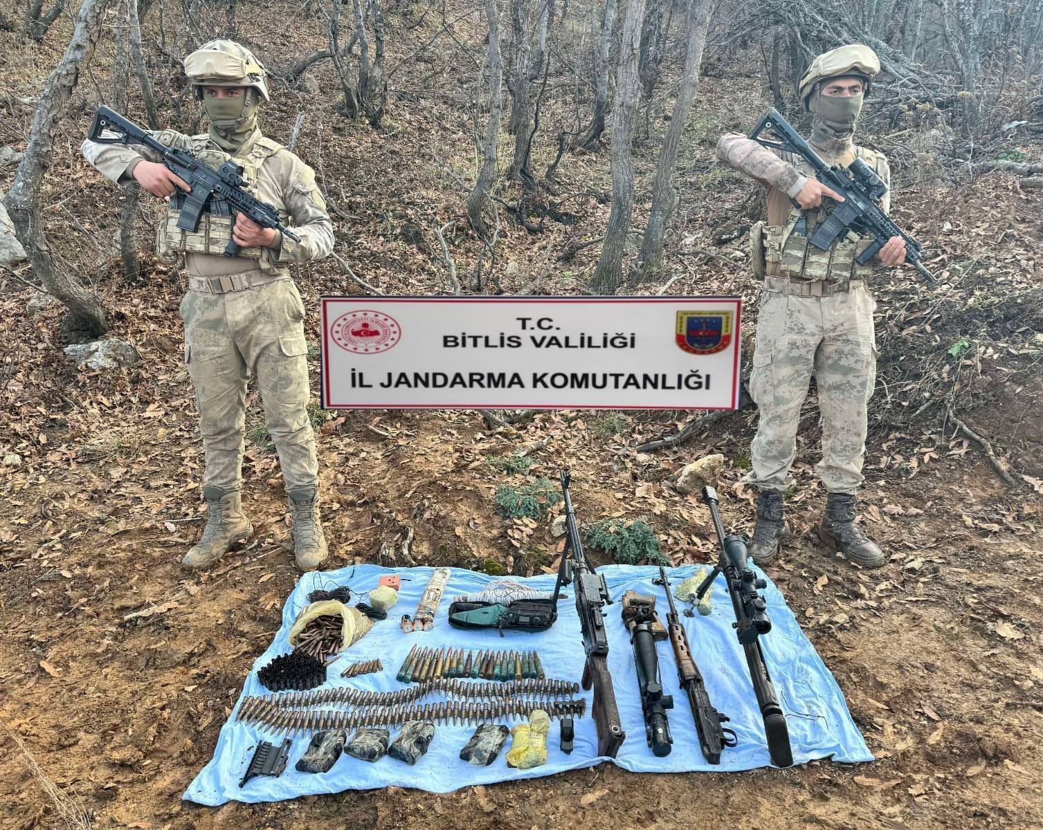 Two Turkish gendarmerie officers pose with a stash of guns and ammunition seized from PKK terrorists during a raid in eastern Bitlis province, Türkiye, Dec. 6, 2023. (DHA Photo)