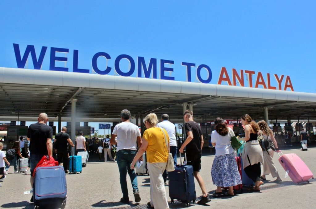 Tourists are photographed in front of the entrance to Antalya Airport in southern Türkiye, Dec. 6, 2023. (IHA Photo)