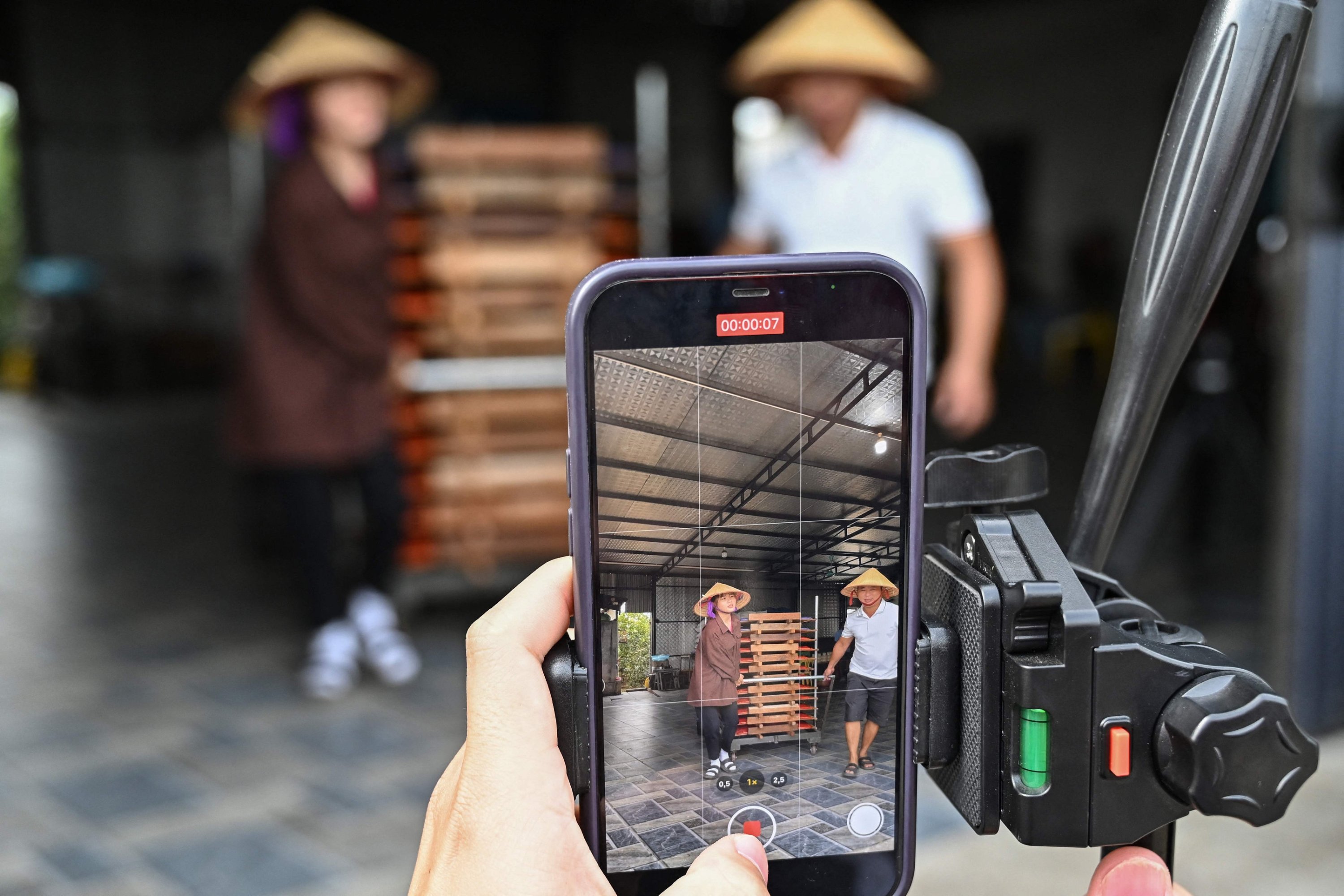 305245 A mobile phone is being used to shoot a video of TikToker Vi Thi Anh taking noodles to drying for TikTok at her workshop in Bac Giang province, Vietnam, Nov. 7, 2023. (AFP Photo)