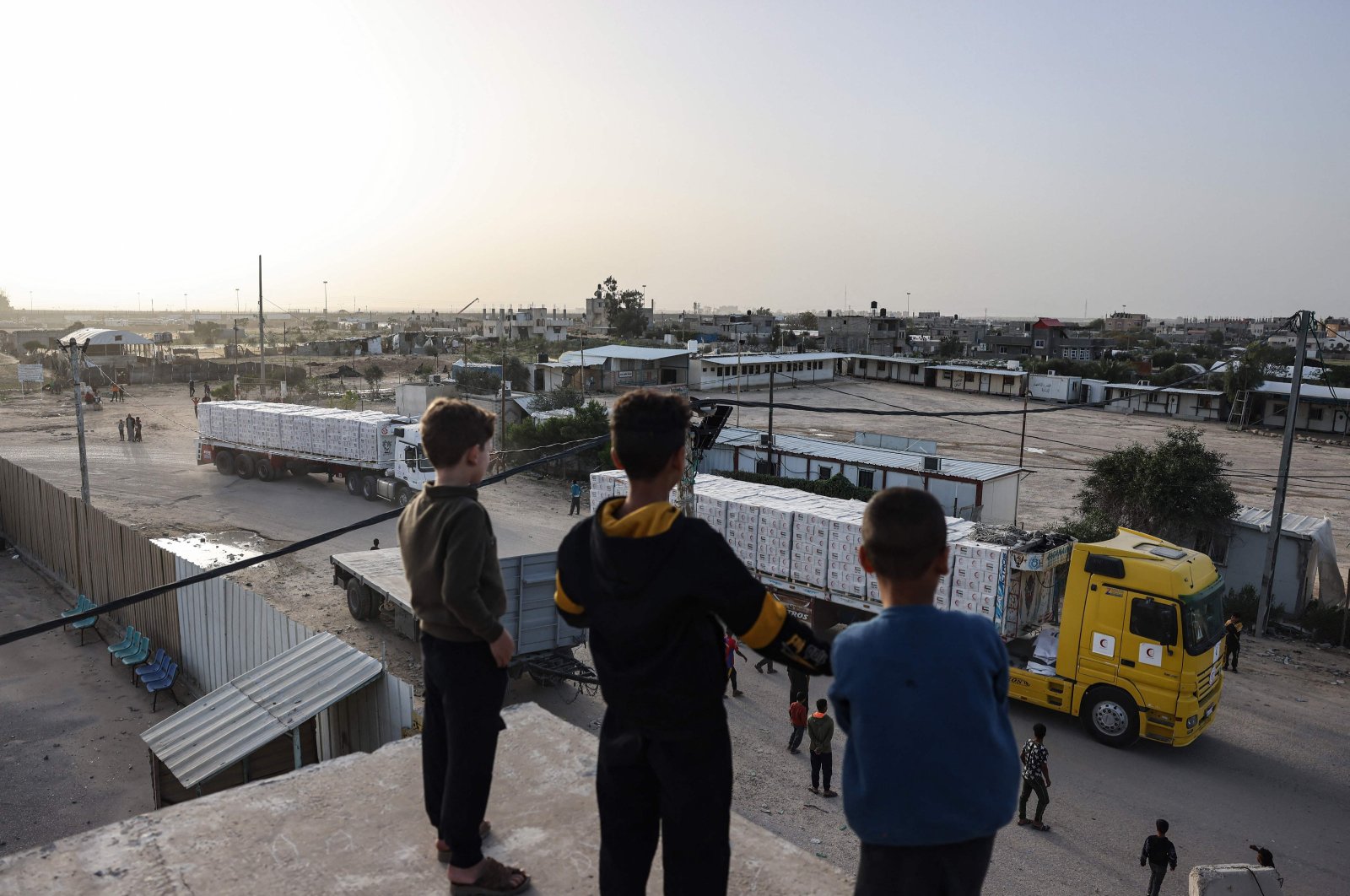 Young boys look at trucks carrying humanitarian aid entering the Gaza Strip via the Rafah crossing with Egypt, Nov. 26, 2023. (AFP Photo)