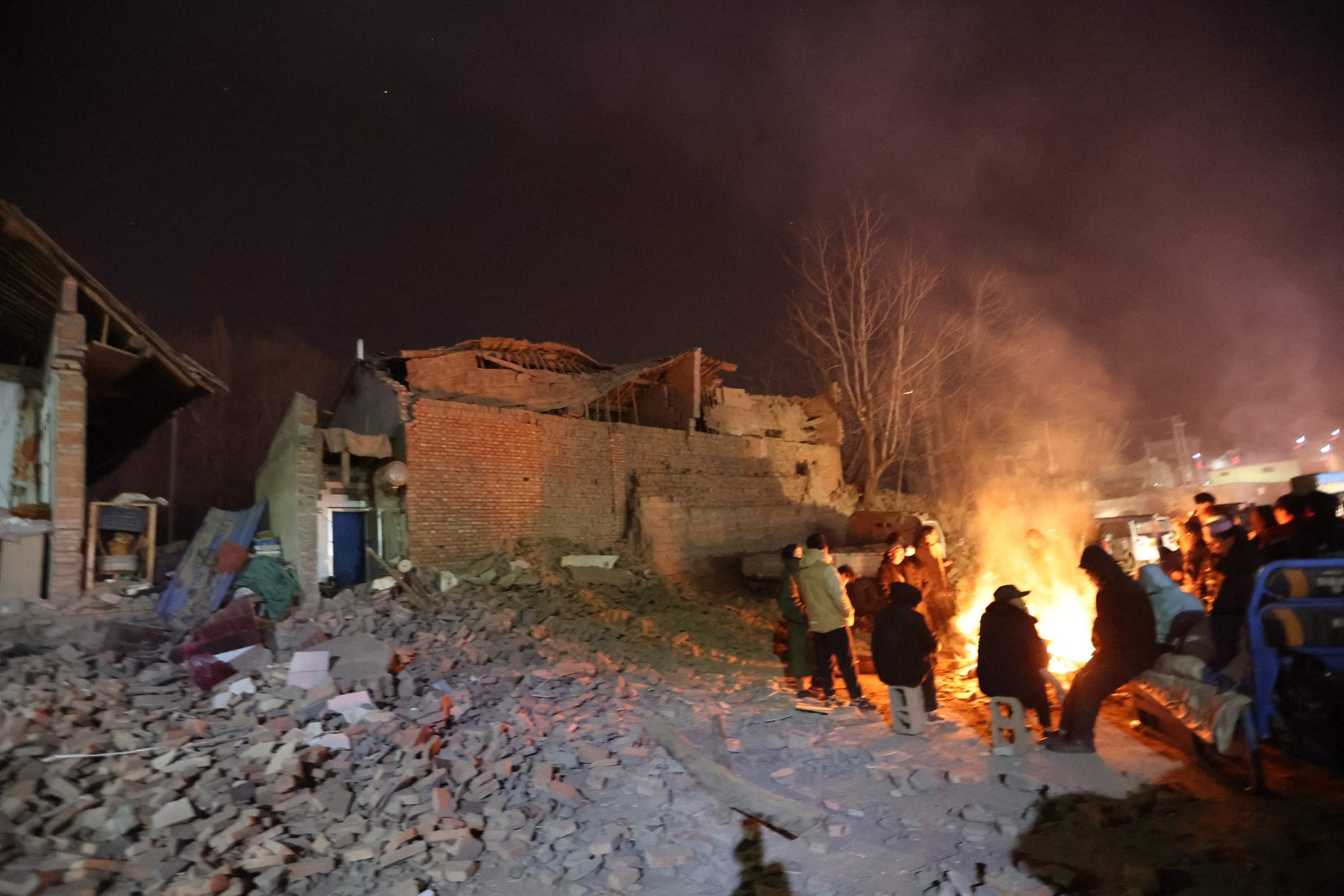 306059 Residents keep warm around a fire in the early morning after an earthquake in Dahejia, Jishishan county, Gansu province in northwest China, Dec. 19, 2023. (AFP Photo)