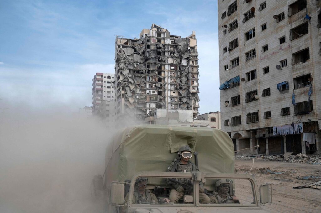 Israeli troops ride a vehicle past damaged buildings during a military operation in the northern Gaza Strip amid continuing battles between Israel and the Palestinian group Hamas, on Nov. 22, 2023. (AFP File Photo)