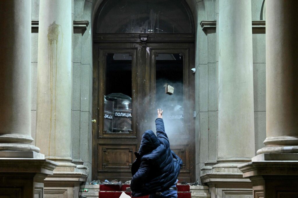 A protester throws a projectile toward police officers using pepper spray inside the Belgrade's city council building during a demonstration in Belgrade, Serbia, Dec. 24, 2023. (AFP Photo)