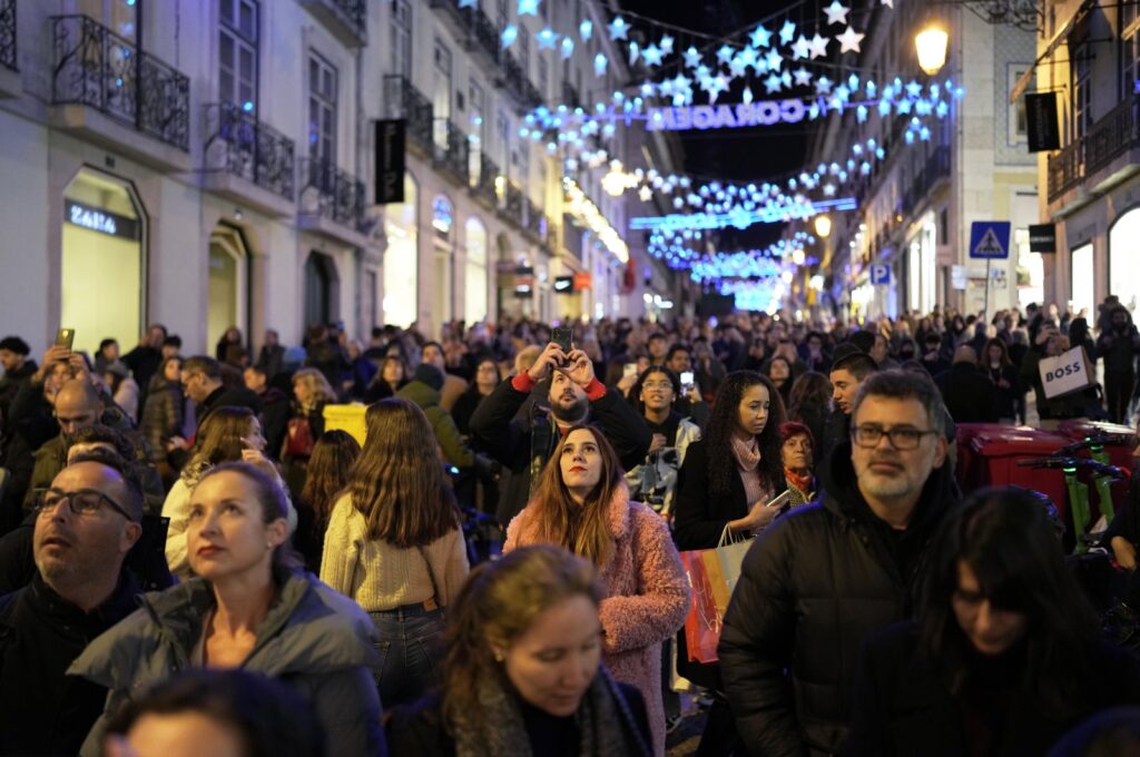 People look up at Christmas lights as crowds stroll around downtown Lisbon's Chiado neighborhood, Portugal, Dec. 23, 2023. (AP Photo)