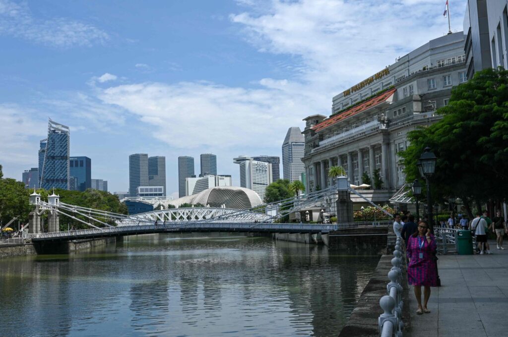 People relax next to a river at the Raffles Place financial district in Singapore, Dec. 5, 2023. (AFP Photo)