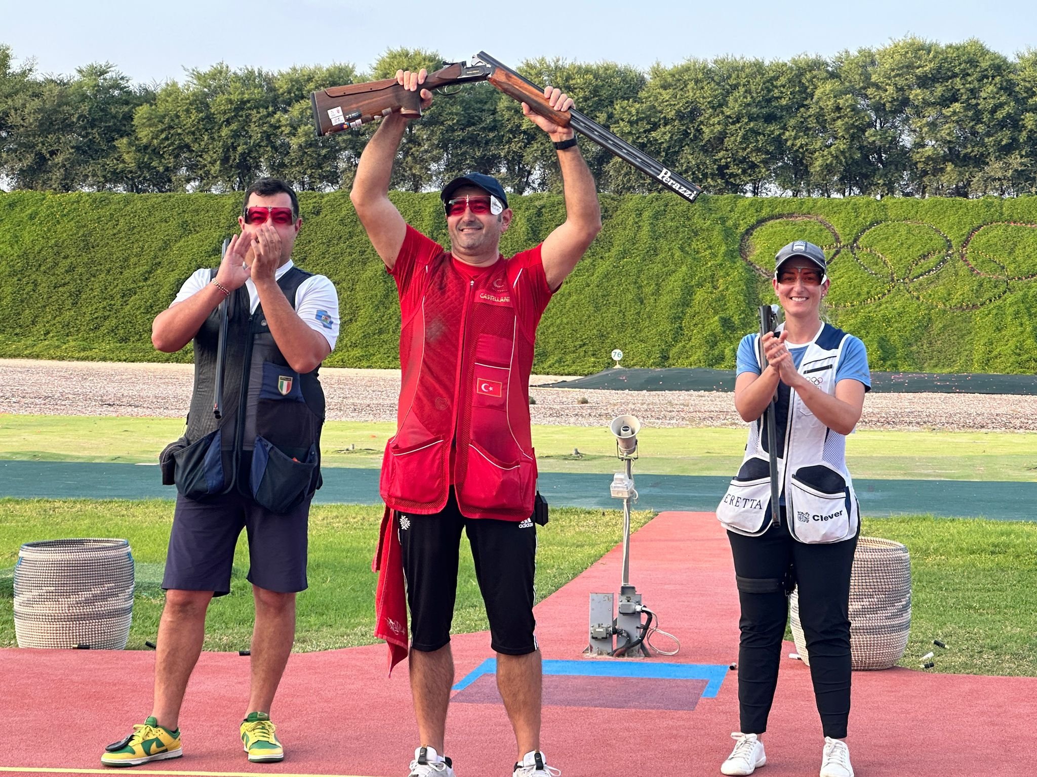 308215 Türkiye's Oğuzhan Tüzün (C) raises the gun after winning gold at the trap super final championships, Doha, Qatar, Dec. 26, 2023. (DHA Photo)