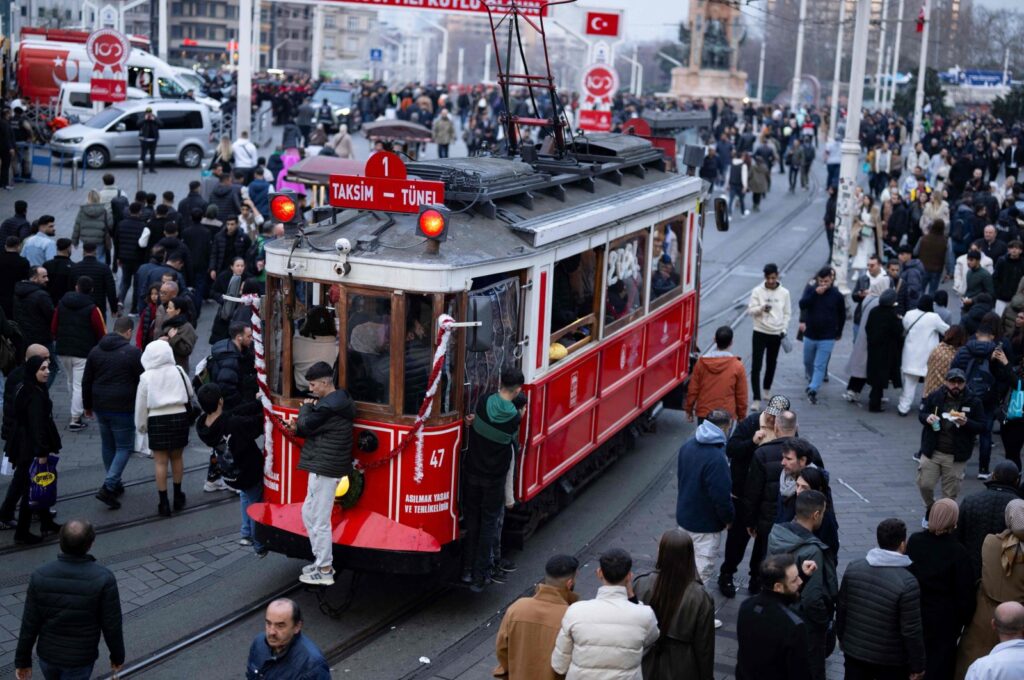 People walk past a historical tramway on Taksim Square during preparations to celebrate the New Year 2024 in Istanbul, Türkiye, Dec. 31, 2023. (AFP Photo)