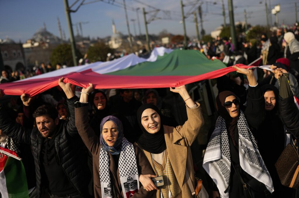 People hold up a giant Palestinian flag as they demonstrate at the Galata bridge landmark to show solidarity with Palestinians amid the ongoing war in Gaza, Istanbul, Türkiye, Jan. 1, 2024. (AP Photo)