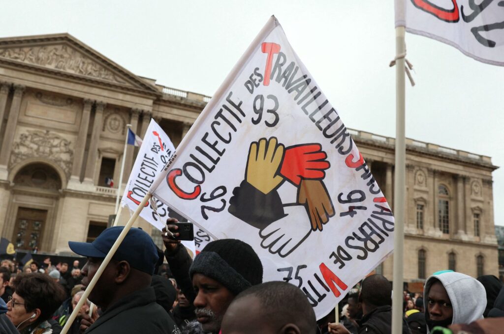 A protester holds a flag during a rally against France's new immigration law at Place du Louvre in Paris, Jan. 25, 2024. (AFP Photo)