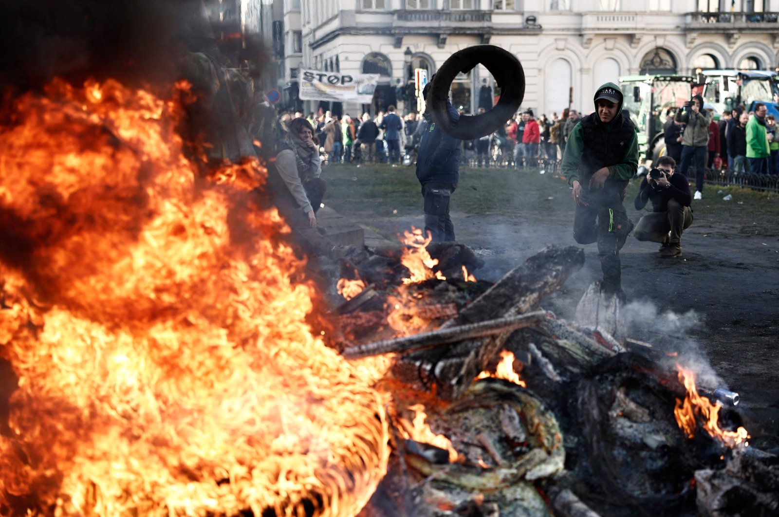 A demonstrator throws a tire in a fire during farmers' protest calling for higher incomes and protection from foreign competition, at Place du Luxembourg near the European Parliament building in Brussels, Belgium, Feb. 1, 2024. (AFP Photo)