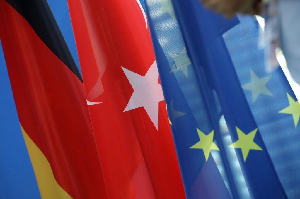 The German (L) and Turkish (C) national flags hang beside a European Union flag during a news conference with then-German Chancellor Angela Merkel and President Recep Tayyip Erdoğan, at the Chancellery in Berlin, Germany, Sept. 28, 2018. (Getty Images Photo)
