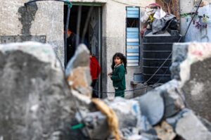 Palestinian children stand outside their home opposite the debris of a building damaged in Israeli bombardment on Rafah in the southern Gaza Strip on Feb. 8, 2024. (AFP Photo)