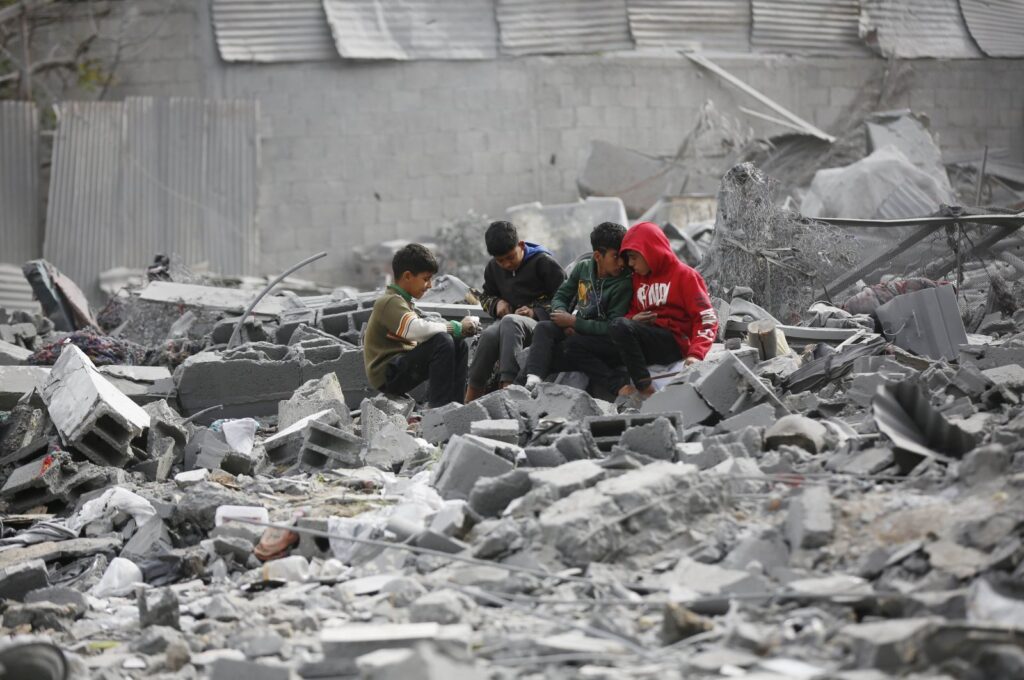 Palestinian children sit among the rubble of a building destroyed in Israeli attacks on Gaza, Palestine, Feb. 13, 2024. (AA Photo)