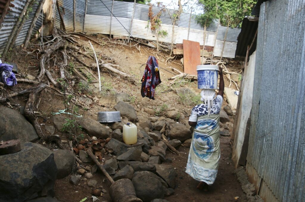 A woman carries a bucket of water on her head on the French Indian Ocean territory of Mayotte, Oct. 12, 2023. (AP Photos)