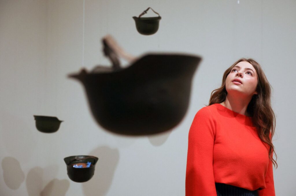 A gallery employee poses with an artwork entitled "Helmets (Pieces of Sky)" by Yoko Ono, Tate Modern, London, U.K., Feb. 13, 2024. (AFP Photo)