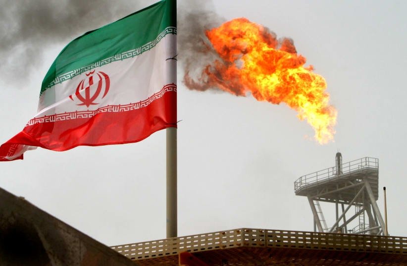 A gas flare on an oil production platform in the Soroush oil fields is seen alongside an Iranian flag in the Persian Gulf, Iran, July 25, 2005. (Reuters Photo)