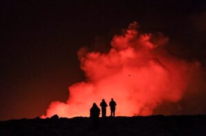 A group of people observe molten lava and billowing smoke from a volcanic eruption near Grindavik, western Iceland, Feb. 8, 2024. (AFP Photo)