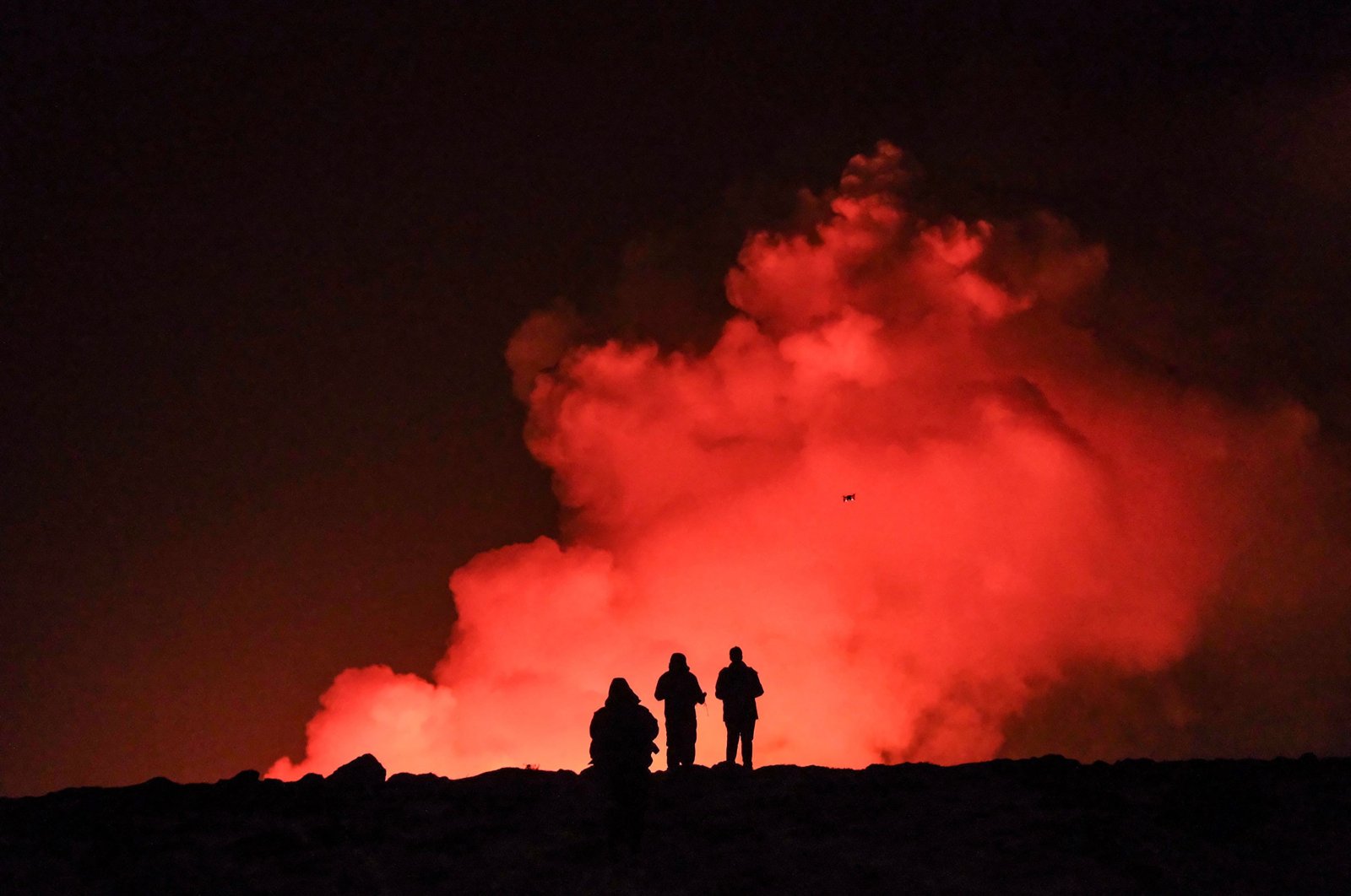 A group of people observe molten lava and billowing smoke from a volcanic eruption near Grindavik, western Iceland, Feb. 8, 2024. (AFP Photo)