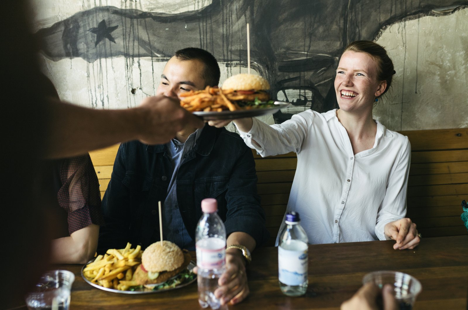 A waiter serving some food to a group of customers in a trendy burger restaurant in Berlin, Germany, Sept. 10, 2018. (Getty Images, File Photo)