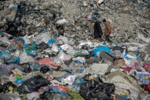 People make their way along a street dumped with garbage in Gaza City, Palestine, Feb. 24, 2024. (Photo by AFP)