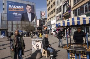 People walk in front of a local election campaign poster of Istanbul mayoral candidate Murat Kurum of the ruling Justice and Development Party (AK Party), on a street in Istanbul, Türkiye, Feb. 27, 2024. (EPA Photo)