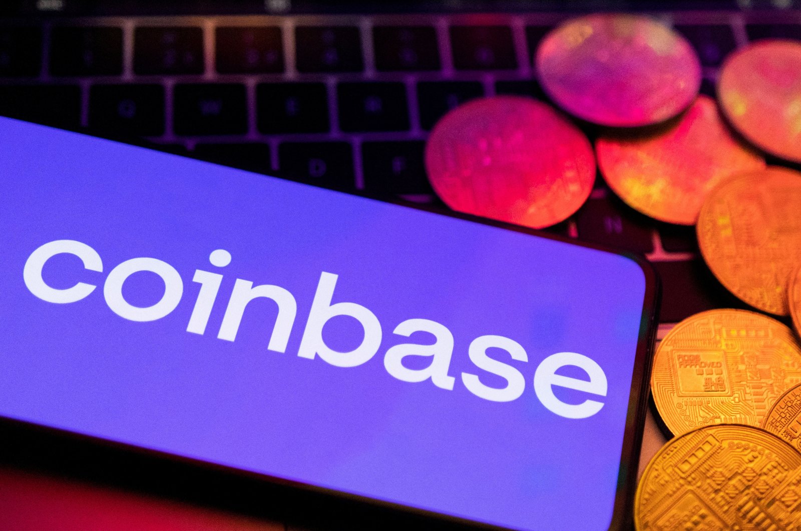 A smartphone with a displayed Coinbase logo and representation of cryptocurrencies are placed on a keyboard in this illustration taken on June 8, 2023. (Reuters Photo)