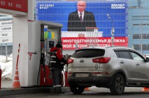 A man works at a petrol station as a large screen shows a live broadcast of the Russian President Vladimir Putin delivering his annual address to the Federal Assembly, in Moscow, Russia, Feb. 29, 2024. (EPA Photo)