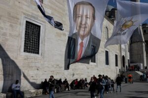 People walk under election posters for President Recep Tayyip Erdoğan and his ruling Justice and Development Party (AK Party) flags in Istanbul, Türkiye, Feb. 20, 2024. (Reuters Photo)