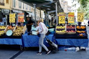 Price tags are seen on fruits as a woman shops at a local market in Nice, France, April 26, 2023. (Reuters Photo)