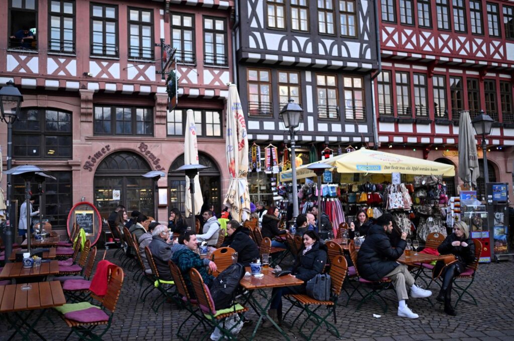 Customers sit at tables of a street cafe on the central Roemer Square in Frankfurt, Germany, Feb. 28, 2024. (AFP Photo)