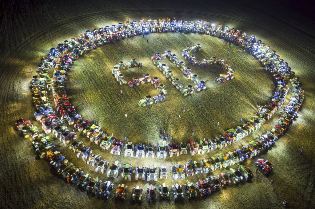 Farmers organize themselves to form a giant "SOS" signal with their tractors as coordinated stunt replicated in various locations across Switzerland, protesting against their work conditions and here specifically the price of milk, echoing numerous protests across Europe in the recents weeks, in a field between the villages of Echallens and Goumoens-la-Ville, Switzerland, Feb. 29, 2024. (AP Photo)