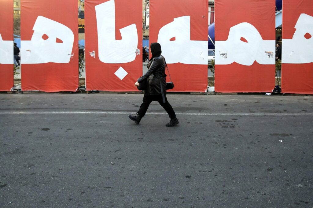 An Iranian woman walks past a huge banner reading in Persian 'All together for homeland' in a street in Tehran, Iran, March 4, 2024. (EPA Photo)