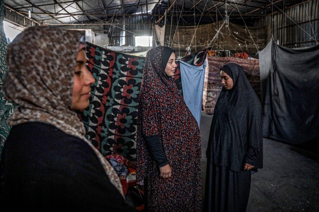 A pregnant Palestinian woman (C) displaced from northern Gaza stands in a warehouse where she is taking shelter, Rafah, Gaza Strip, Palestine, Feb. 29, 2024. (AFP Photo)