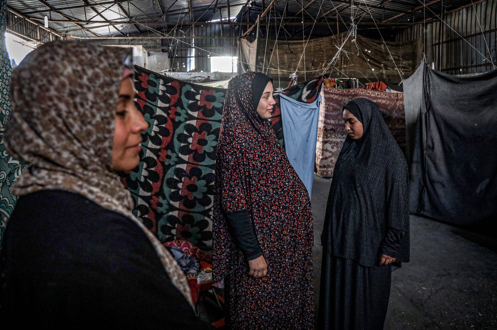 A pregnant Palestinian woman (C) displaced from northern Gaza stands in a warehouse where she is taking shelter, Rafah, Gaza Strip, Palestine, Feb. 29, 2024. (AFP Photo)