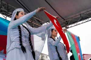 Two Azerbaijani women in local clothes raise Turkish and Azerbaijani flags as a part of Nevruz celebrations, Ankara, Türkiye, March 21, 2021. (Shutterstock Photo)