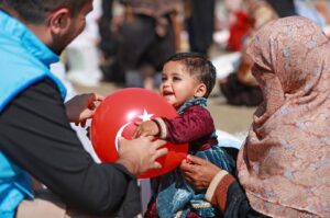 A TDV volunteer gives a Turkish-flagged balloon to a child in Pakistan, March 15, 2024. (AA Photo)