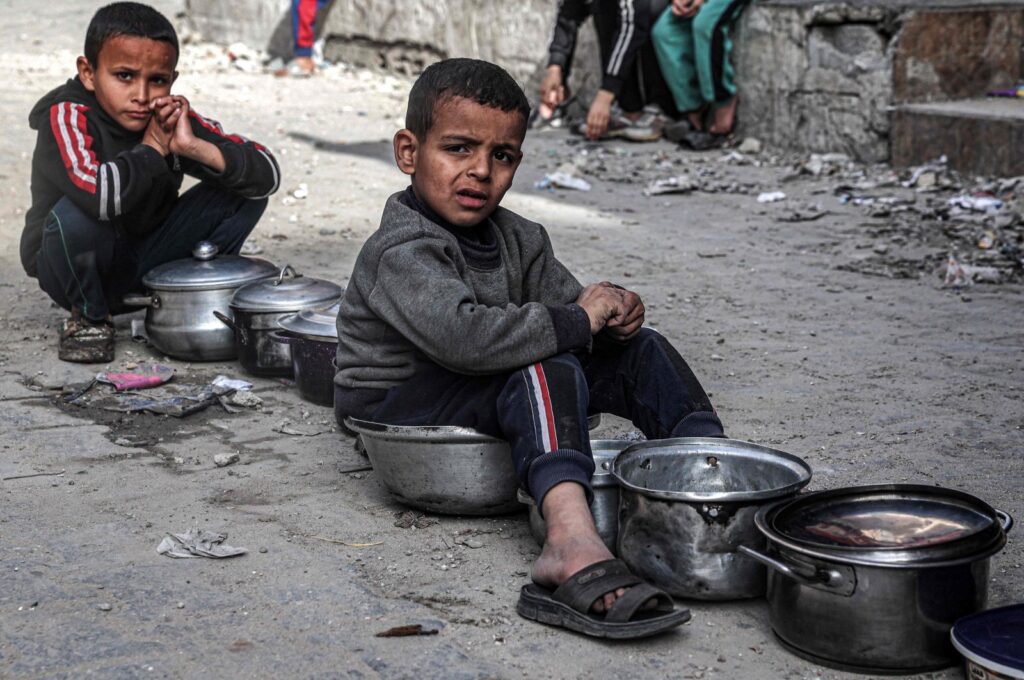 Boys sit with empty pots as displaced Palestinians wait for meals provided by a charity organization ahead of the fast-breaking "iftar" meal during Islam's holy month of Ramadan, in Rafah, southern Gaza Strip, Palestine, March 16, 2024. (AFP Photo)