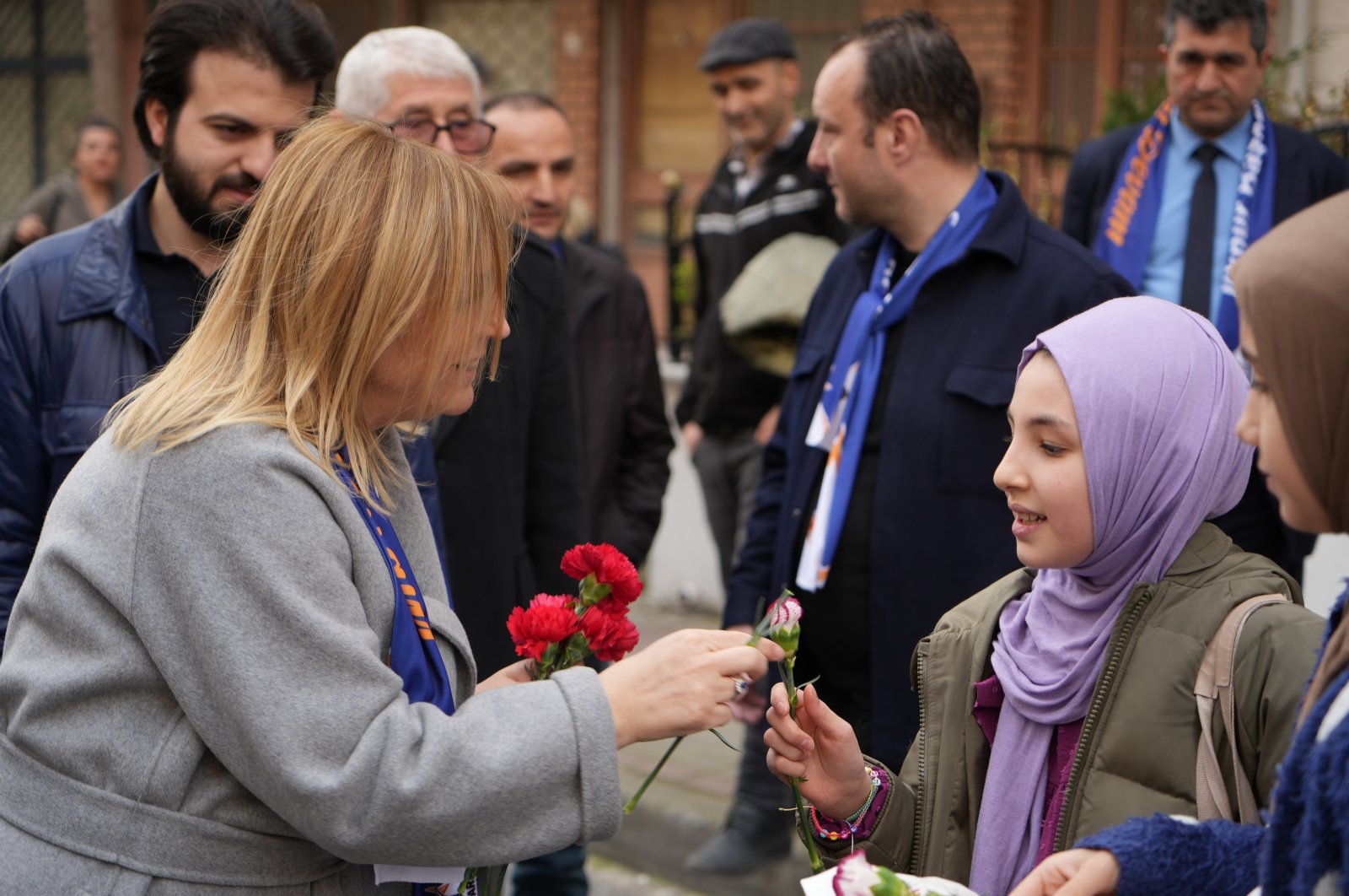 Ilknur Kovaç Bayraktar (L), the ruling Justice and Development Party's (AK Party) mayoral candidate for an Istanbul district, hands out flowers to citizens during a neighborhood tour, Istanbul, Türkiye, March 20, 2024. (IHA Photo)