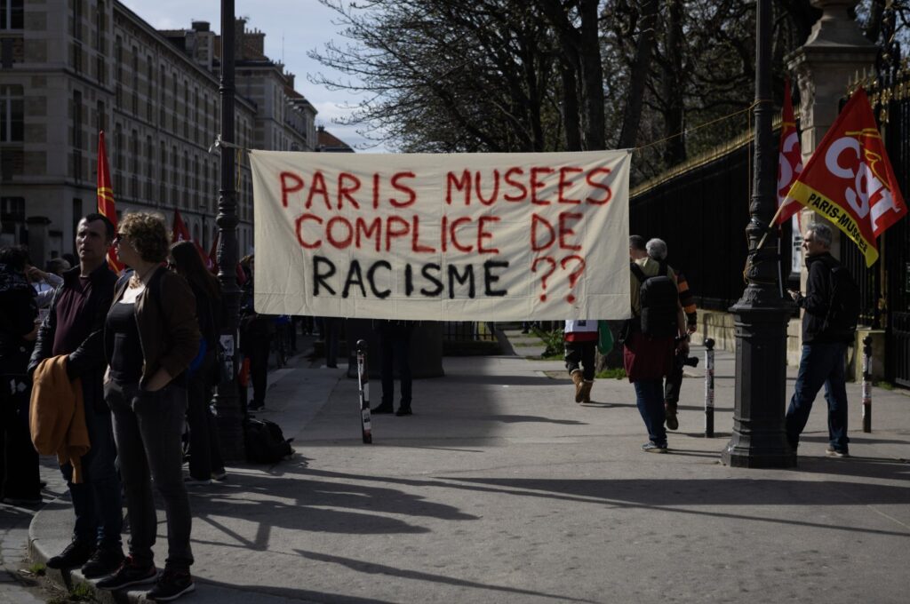 A banner reading Paris Musees complicit in racism at a demonstration for the public service mobilization day, Paris, March 19, 2024. (Reuters Photo)