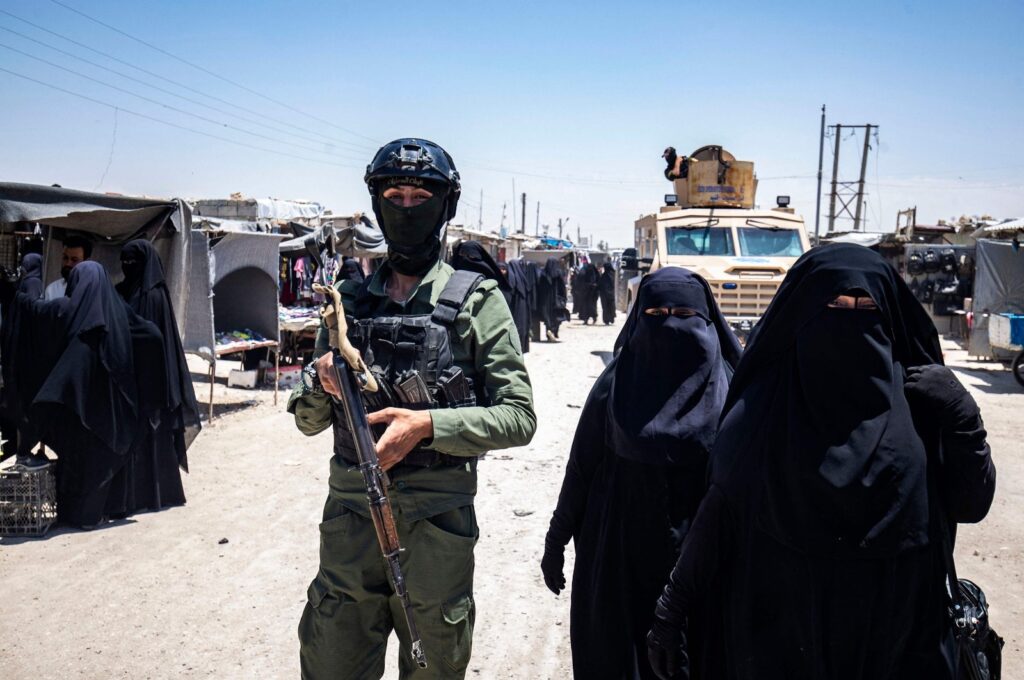 Women walk past a YPG/PKK terrorist at the YPG/PKK-run al-Hol camp holding families of Daesh terrorists, northeastern al-Hassakeh Governorate, Syria, Oct. 10, 2023. (AFP Photo)