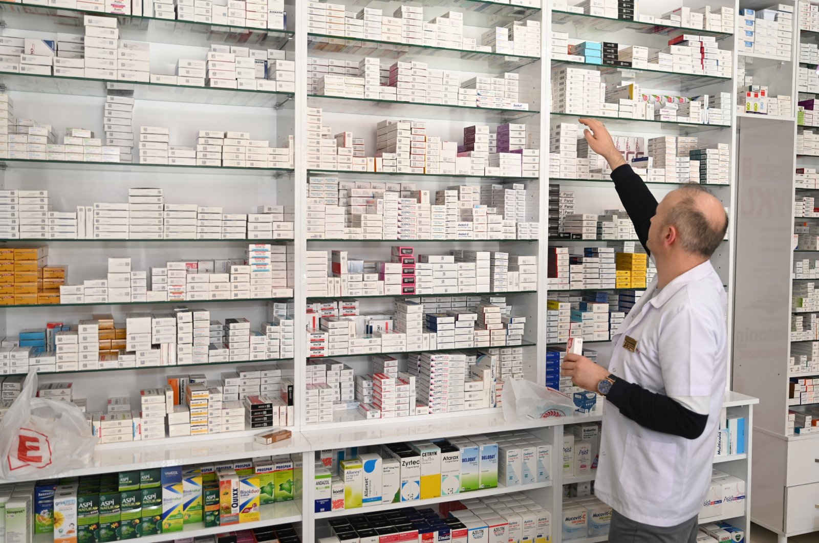 A pharmacist is seen picking out some medicine boxes from a rack in a pharmacy, Konya, Türkiye, on March 29, 2024. (AA Photo)