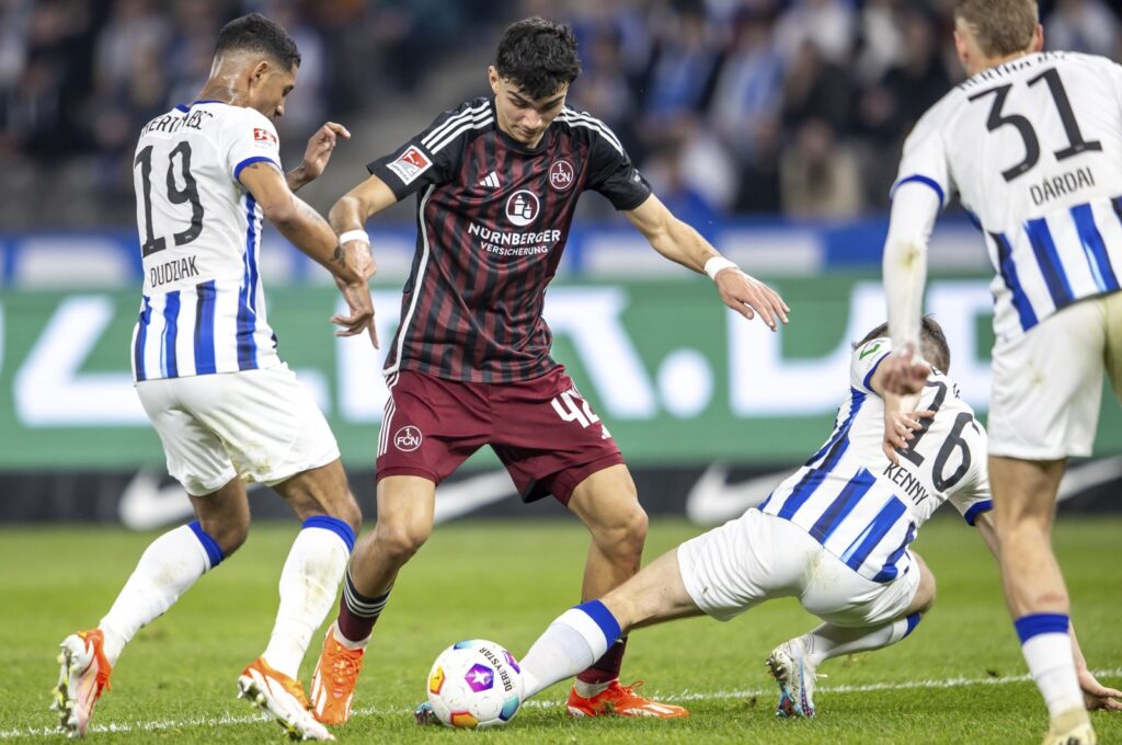 Nuremberg's Can Uzun (C) vies for the ball with Berlin's Jeremy Dudziak (L) and Jonjoe Kenny during the Bundesliga second division match, March 30, 2024. (AP Photo)