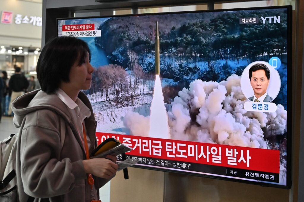 A woman walks past a television screen showing a news broadcast with file footage of a North Korean missile test, at a railway station in Seoul on April 2, 2024. (AFP Photo)