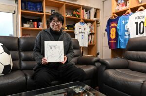 Japanese cartoonist and manga artist Yoichi Takahashi, best known for his work "Captain Tsubasa," displays his autograph with the painting of the main character following an interview at his workplace in Tokyo, Japan, Jan. 30, 2023. (AFP Photo)