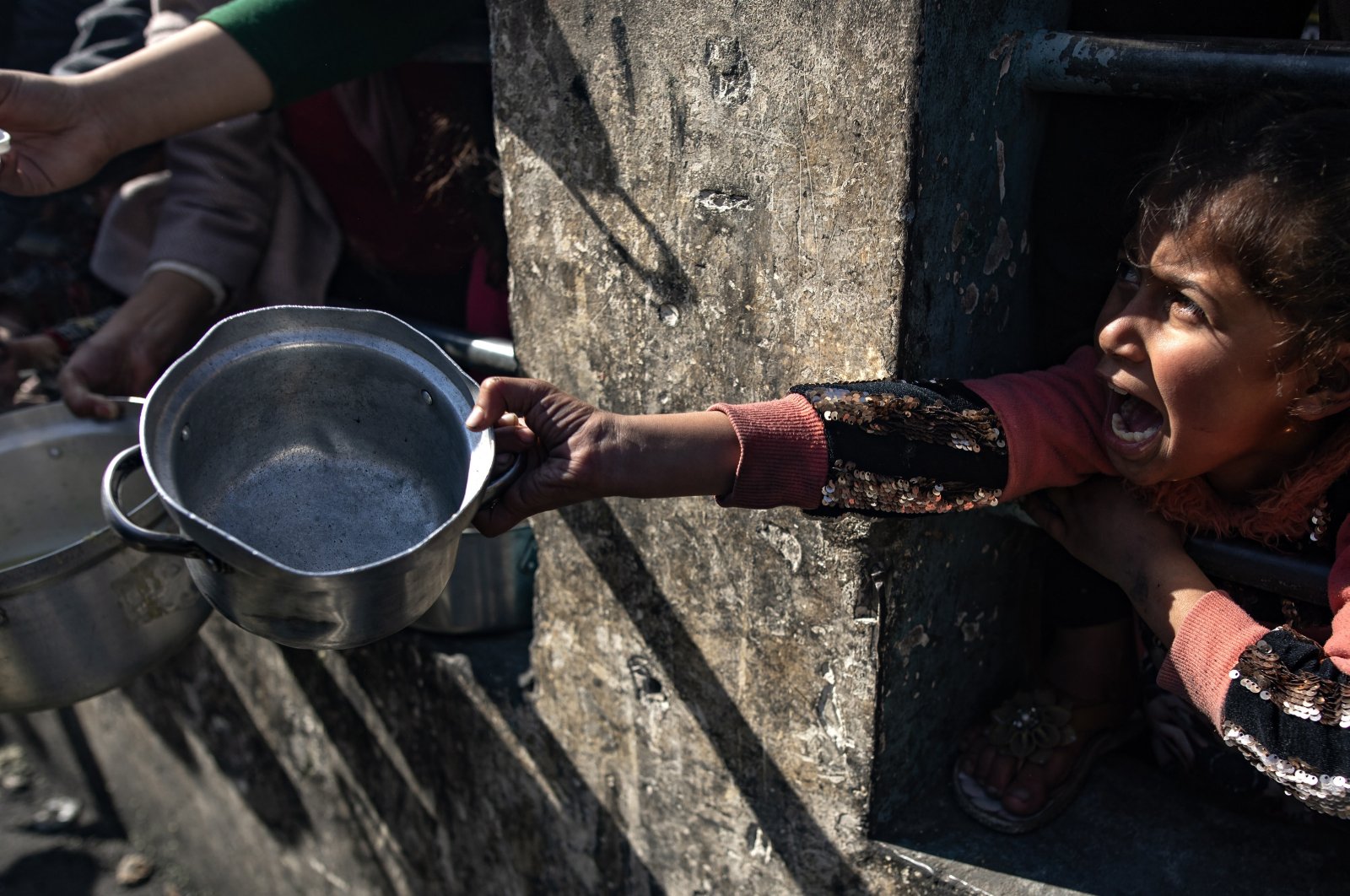 A displaced Palestinian child holds up an empty pot as she waits with others to receive food aid provided by a Palestinian youth group in the Rafah refugee camp, Gaza Strip, Palestine, Jan. 25, 2024. (EPA Photo)